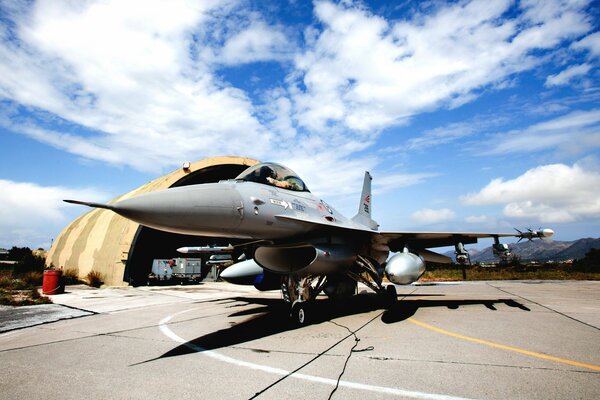 Combattente vicino all hangar con cielo blu