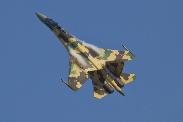 The Su-35S fighter is flying in the blue sky