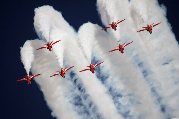 Queues blanches de fumée derrière les avions rouges au spectacle aérien