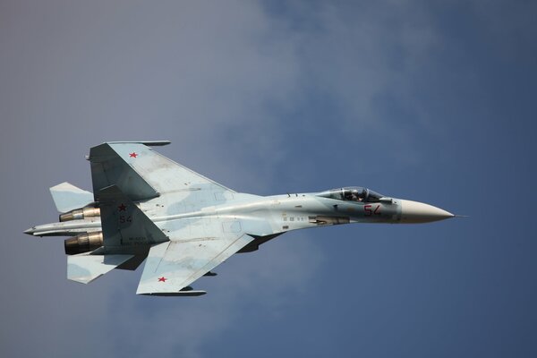 A Russian fighter jet is flying in the blue sky.