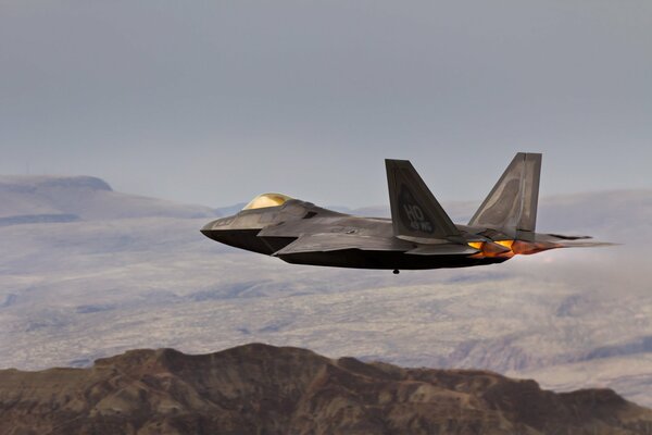 Raptor military aircraft in the sky over the mountains