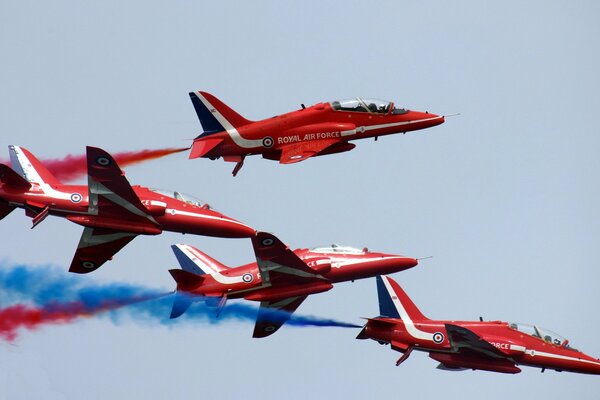 Contra el cielo despejado, los aviones rojos liberan humo multicolor