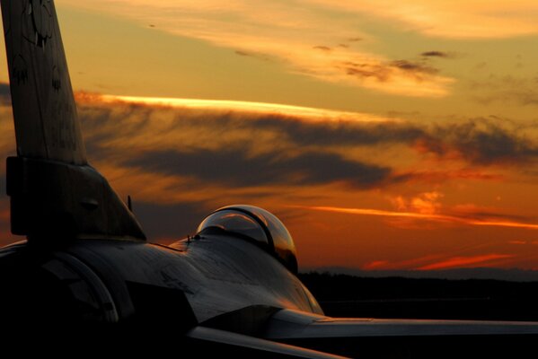 A fighter wing is visible at a beautiful sunset