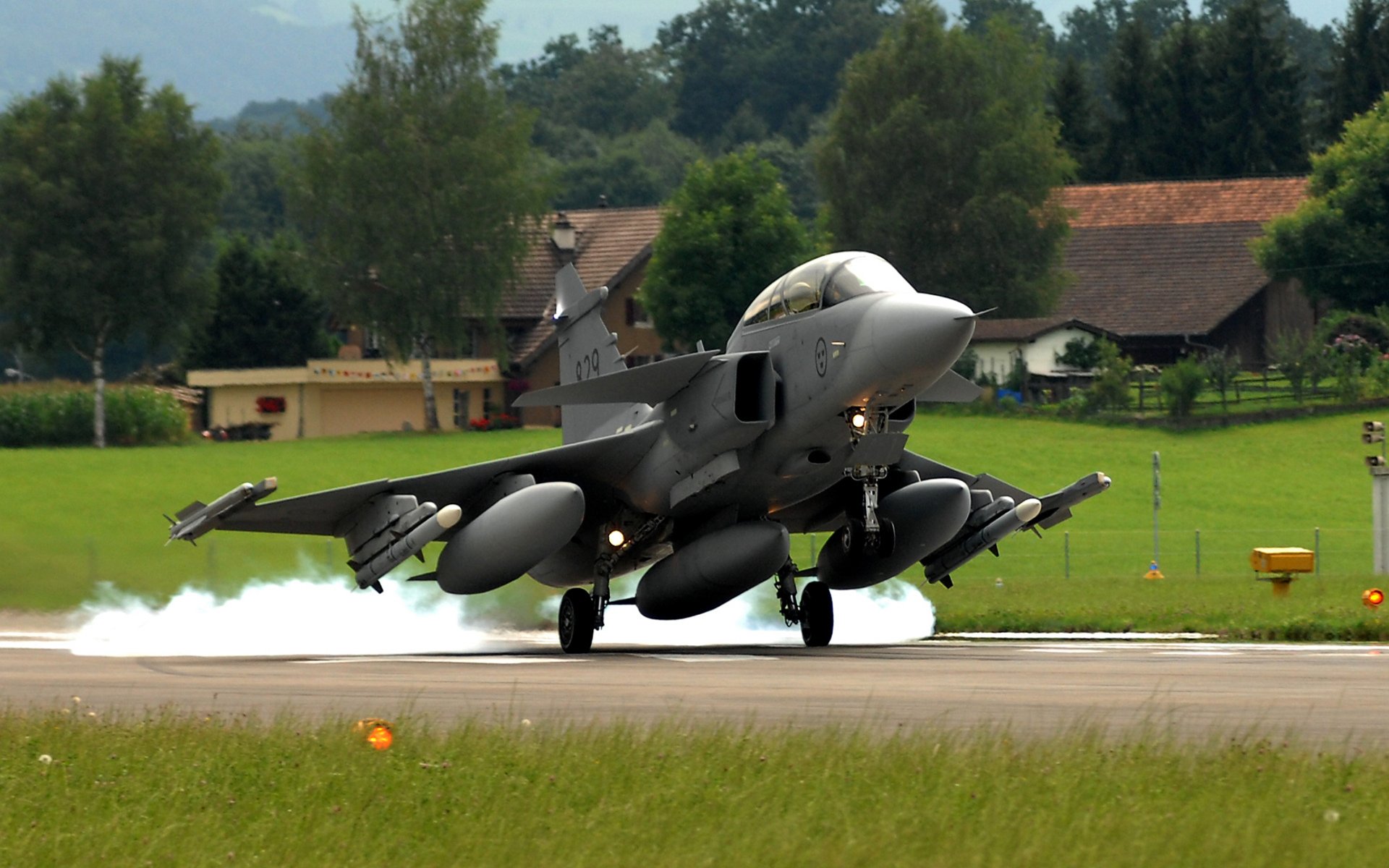 avion saab jas 39 gripen suédois polyvalent combattant quatrième génération décollage photo aérodrome bande herbe arbres maisons