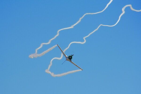 Avión en el cielo azul con una cola de humo