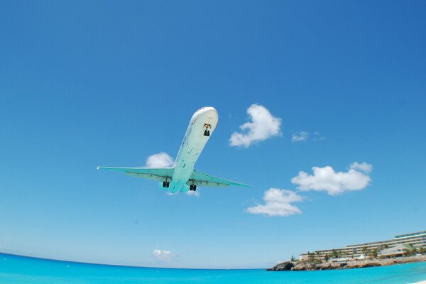 El avión vuela sobre el océano limpio y sobre los hoteles