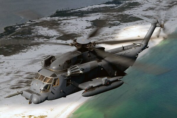 Grauer Hubschrauber, der über dem Meer fliegt