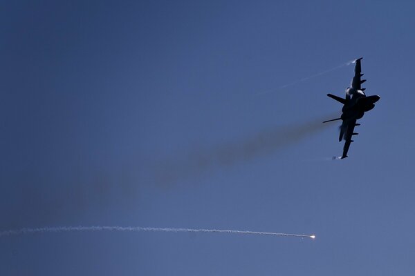 The plane is flying in the sky leaving a smoke trail