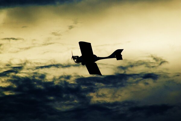 Dark plane flying against dark clouds