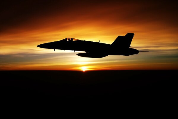 Un avión oscuro vuela en medio de una hermosa puesta de sol