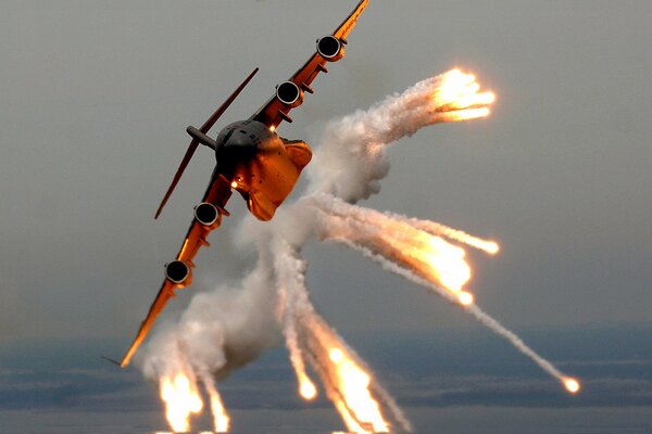 Un enorme aereo che vola nel cielo rilascia fuoco e fumo