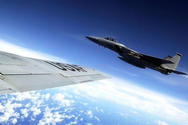 Foto de un avión volando alto en el cielo con el ala de otro avión