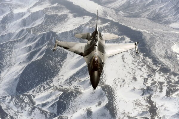 A combat aircraft flies over the snow-capped mountains