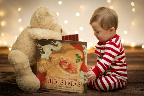 Un enfant en pyjama rayé lit un livre et s assoit avec un jouet