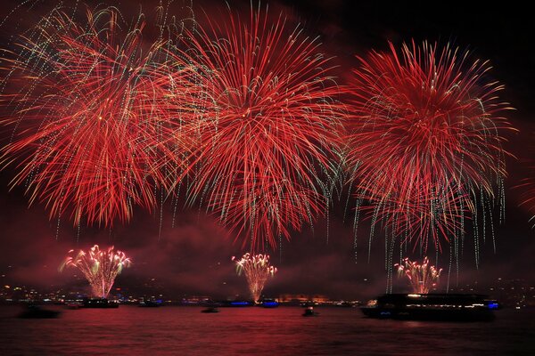 Fuegos artificiales y fuegos artificiales por la noche sobre el agua