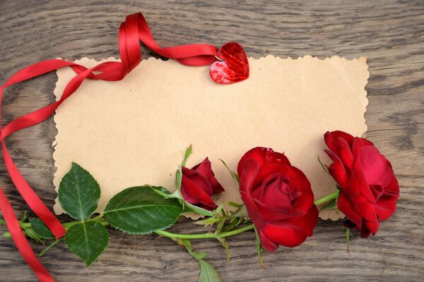 Rose rosse, pergamena e nastro rosso con medaglione a forma di cuore