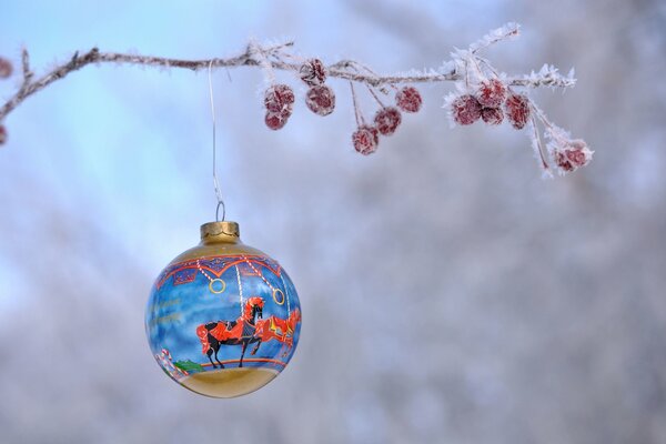 Christmas ball on a snow-covered branch with winter berries