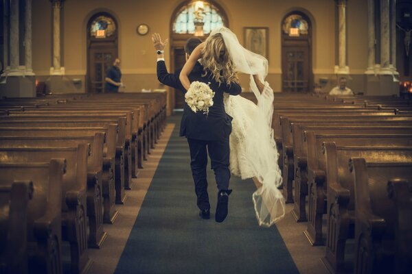 The groom carries the bride through the church