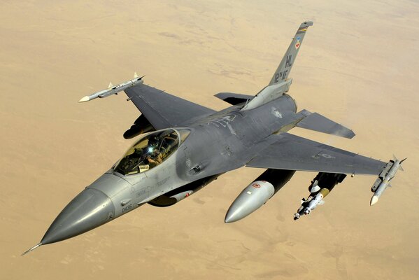 El F-16 vuela por el cielo sobre el desierto