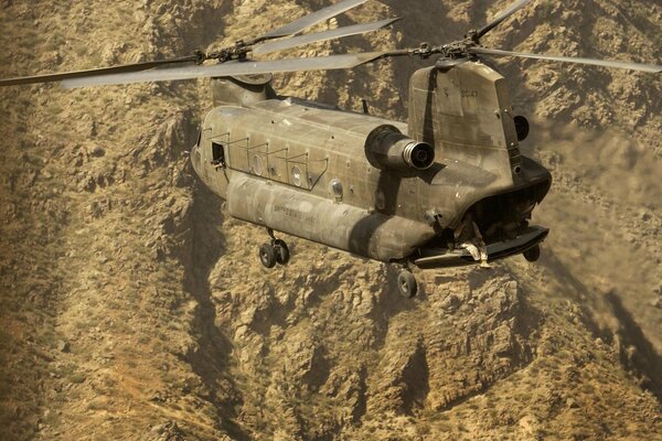 A masked coloring helicopter flies over the mountains