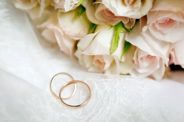 Anillos de boda junto a rosas blancas