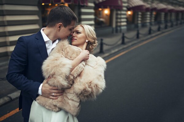 The bride and groom embrace against the background of the street