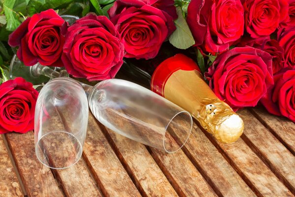 A glass with a bottle of champagne and red roses