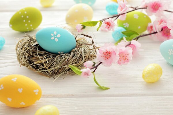 An Easter egg in a basket. Beautiful flowers. Colorful eggs on the table