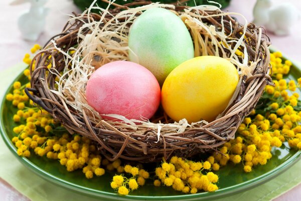 Tre uova di Pasqua in un cesto e mimosa