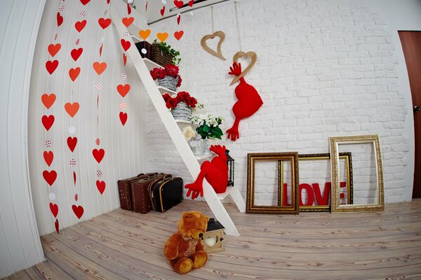 Studio fotografico decorato per il giorno di San Valentino con cuori murali, cornici, cuscini e un orso