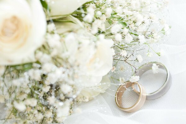 Two wedding rings on the fabric next to the bouquet