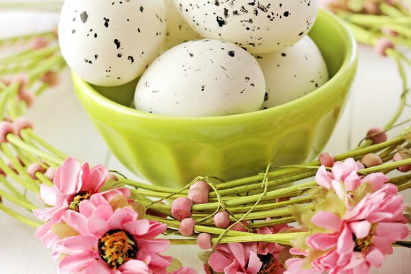 Oeufs de Pâques en marbre dans un bol vert clair sur fond de Couronne de fleurs roses