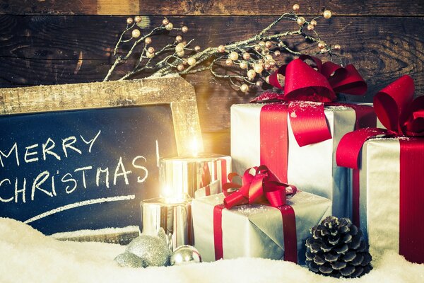 Geschenke in Kisten, Kerzen und Inschrift: Frohe Weihnachten