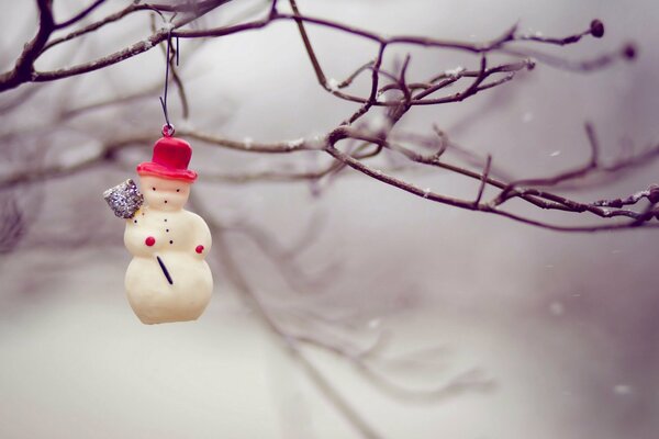 Muñeco de nieve en un árbol en invierno nevado