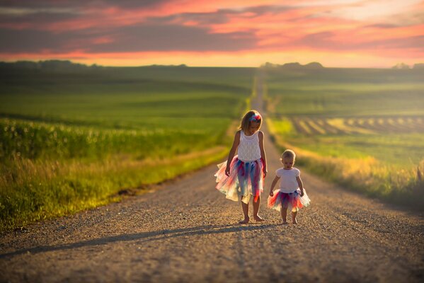 Girls wander along the road among the endless fields