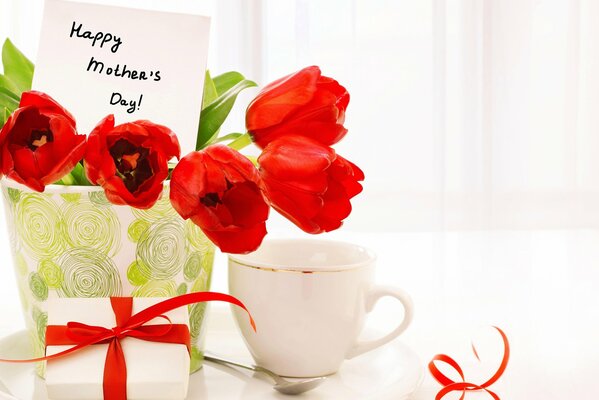 Very beautiful tulips with a postcard on the table and a gift