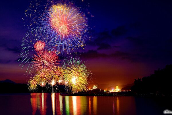 Fireworks in the night sky, which is reflected in the lake