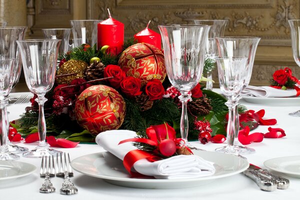 New Year s table setting with forfor glasses, white napkins and a Christmas wreath decorated with bright red large balls on a background of tall red candles