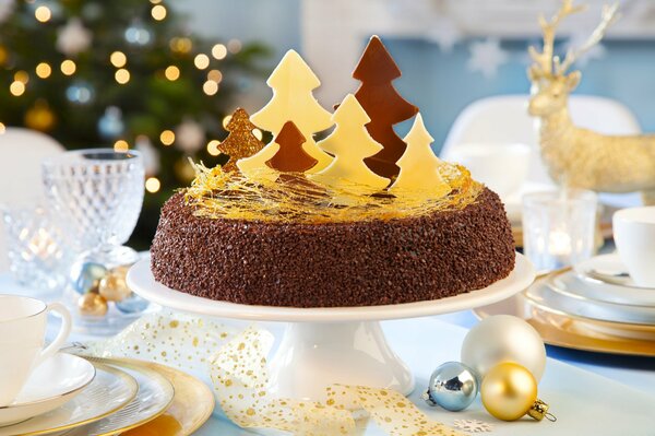 Pastel de Navidad hecho en casa con trozos dulces en el fondo de la radiante belleza de Navidad árbol de Navidad Deer bolas de Navidad y hermosa vajilla blanca