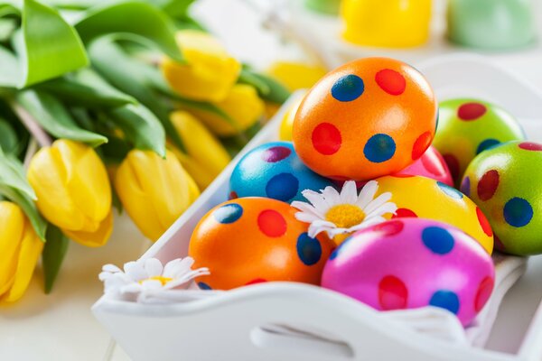 Huevos de Pascua multicolores con tulipanes en la mesa