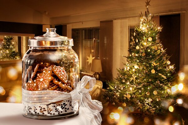 Gemütliches Glas mit Keksen auf dem Hintergrund eines Weihnachtsbaumes