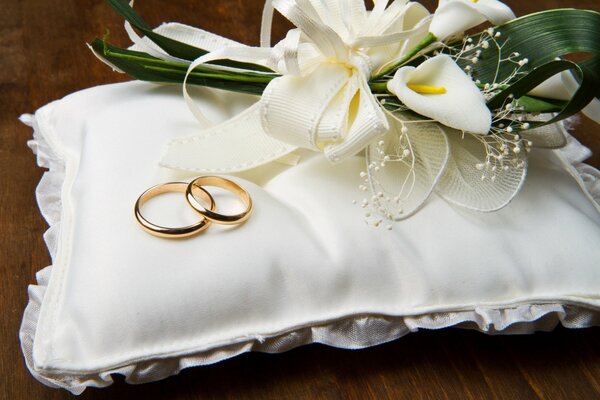 Anillos de boda en almohada blanca