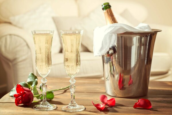 Two glasses and champagne in a bucket on the table