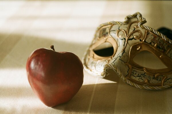 Maschera di carnevale e grande mela rossa all ombra della stanza