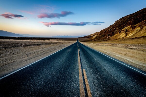 Camino al atardecer en el desierto con montañas