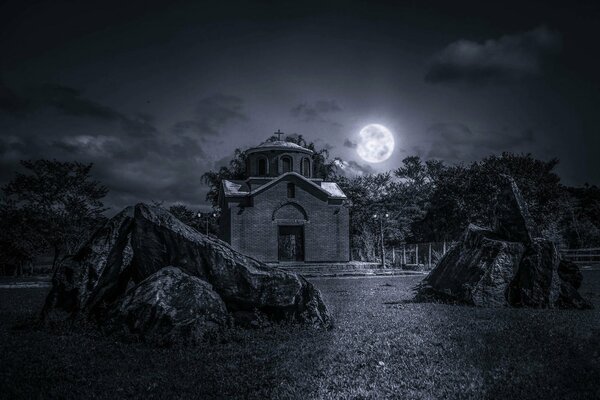 Nachthimmel. Die Kirche ist unter dem Mond. Der Mond erhellt das Gras