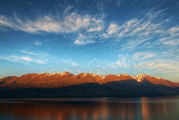 Mountain landscape in the reflection of the water surface with a clear blue sky