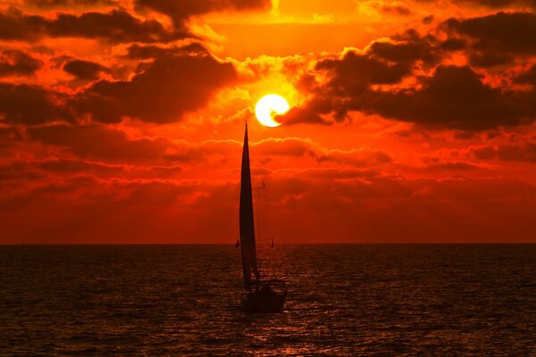 Yacht im Meer unter einem scharlachroten Sonnenuntergang