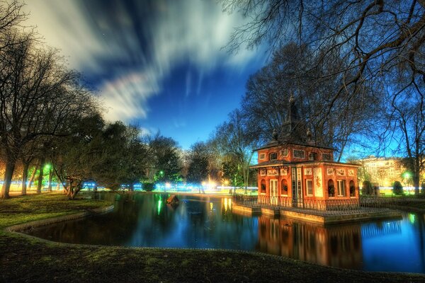 A house in the park by a pond with beautiful clouds