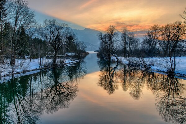 El río de invierno refleja el resplandor del cielo